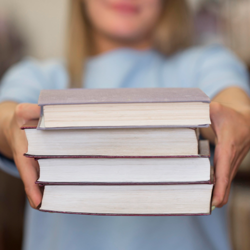 person holding out a stack of books